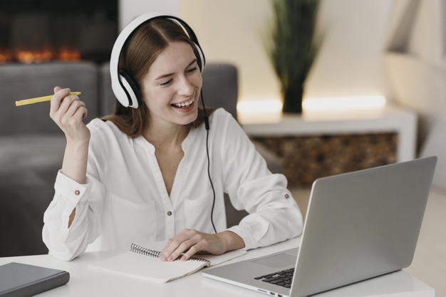 Smiling young woman in headphones doing online classes