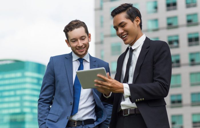 Closeup of Smiling Coworkers Using Tablet Outdoors
